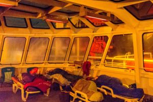 The huddled forms of sleepers on white plastic lounge chairs, grilling under heat lamps on the deck of a ferry headed to Alaska